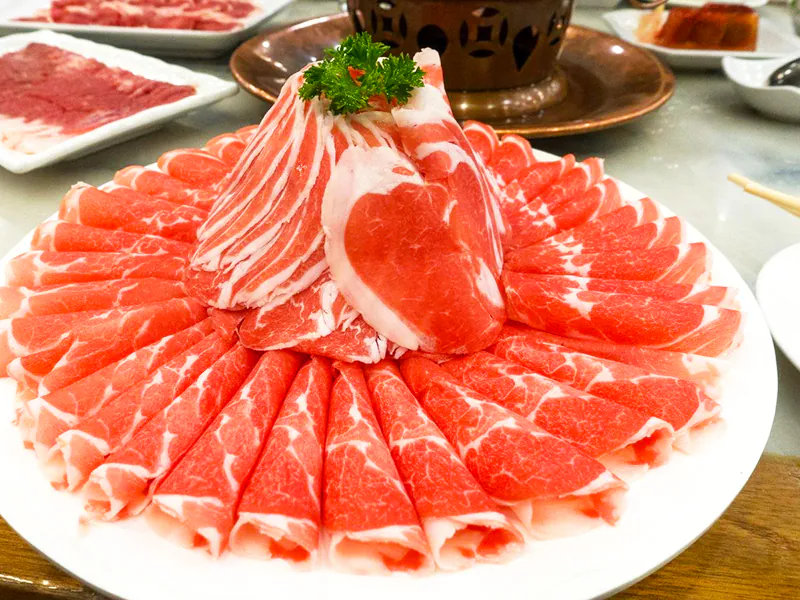 Sliced lamb rolls arranged in a beautiful flower shape on a white plate at Beijing Hot Pot Restaurant, a Hot Pot Restaurant in Portland